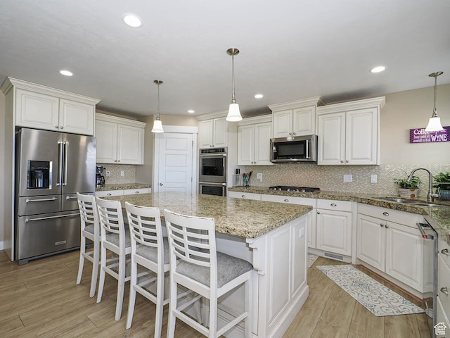 7503 S Bridge Maple Ln, West Jordan, UT 84081 - kitchen featuring appliances with stainless steel finishes, a sink, a center island, light wood-style floors, and tasteful backsplash