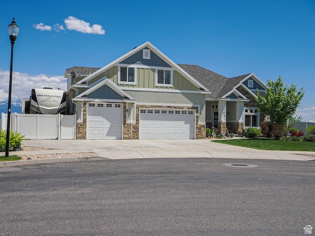 7503 S Bridge Maple Ln, West Jordan, UT 84081 - view of front of home featuring fence, stone siding, an attached garage, board and batten siding, and driveway
