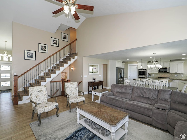 7503 S Bridge Maple Ln, West Jordan, UT 84081 - living room with a chandelier, high vaulted ceiling, a ceiling fan, light wood-type flooring, and stairs