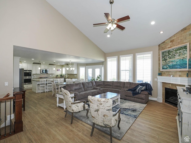 7503 S Bridge Maple Ln, West Jordan, UT 84081 - living room featuring ceiling fan, high vaulted ceiling, a fireplace, light wood-type flooring, and a chandelier
