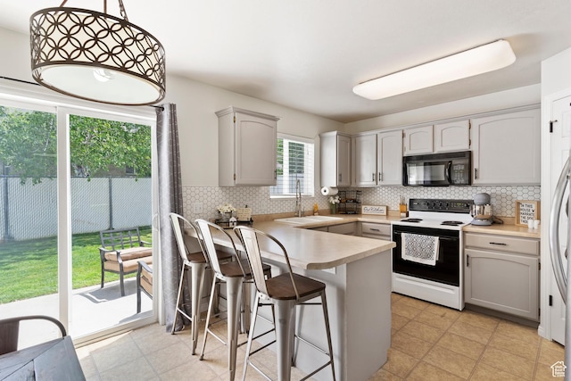 kitchen with black microwave, electric stove, a sink, a peninsula, and tasteful backsplash