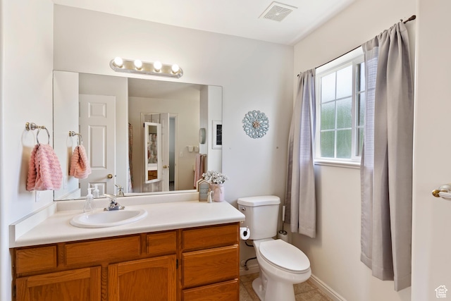 bathroom with toilet, vanity, tile patterned floors, and baseboards