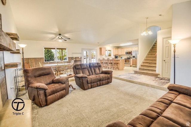 living area with ceiling fan, light colored carpet, stairs, and vaulted ceiling