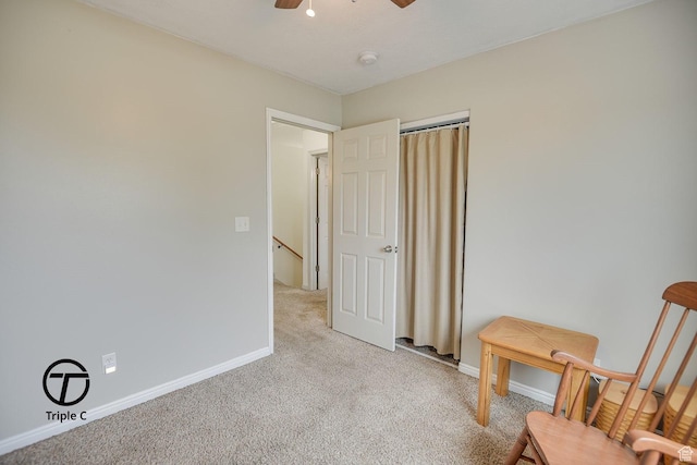 sitting room with light carpet, ceiling fan, baseboards, and an upstairs landing