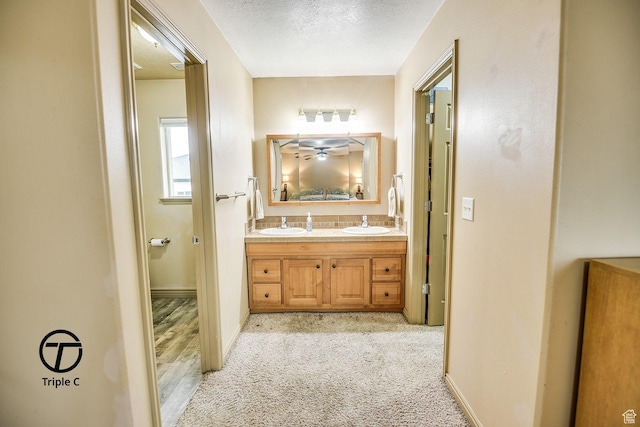 bathroom featuring a textured ceiling, double vanity, and baseboards