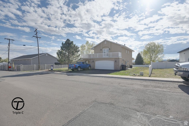 view of front of home with asphalt driveway, stucco siding, an attached garage, fence, and a balcony
