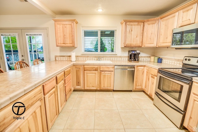 kitchen with stainless steel appliances, light brown cabinetry, a sink, healthy amount of natural light, and recessed lighting