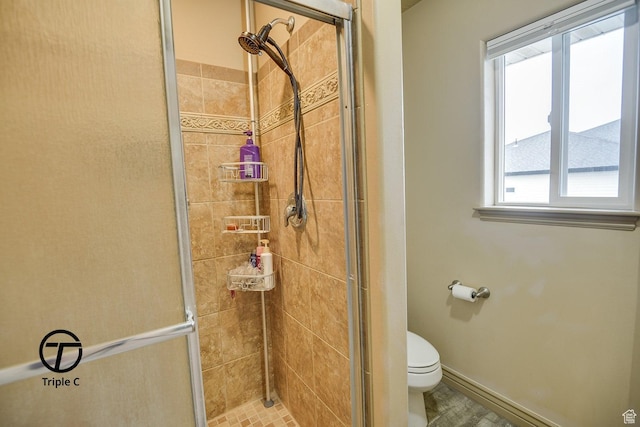 full bath featuring toilet, a shower stall, and baseboards