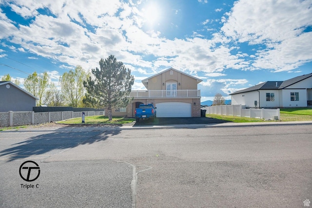 view of front of property with an attached garage, fence, driveway, and a balcony