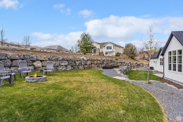 view of grassy yard featuring an outdoor fire pit and a residential view