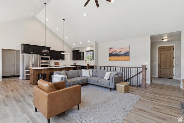 living area with high vaulted ceiling, ceiling fan, light wood finished floors, baseboards, and recessed lighting