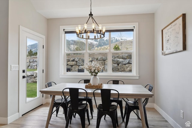dining room featuring a chandelier, baseboards, and light wood-type flooring