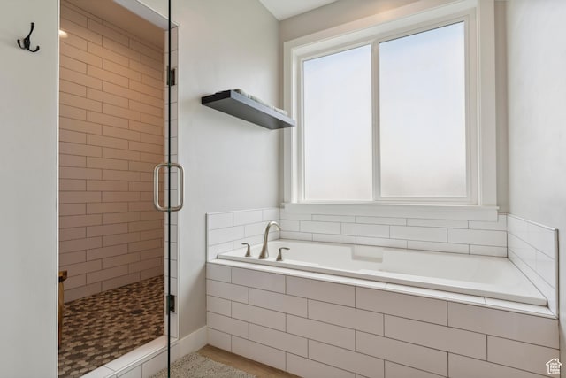 full bathroom with healthy amount of natural light, a shower stall, and a garden tub