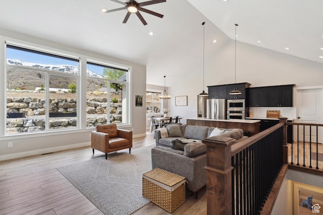 living area featuring a ceiling fan, high vaulted ceiling, light wood-style flooring, and recessed lighting