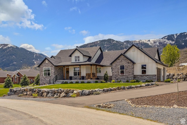 view of front of house featuring board and batten siding, a mountain view, stone siding, and covered porch
