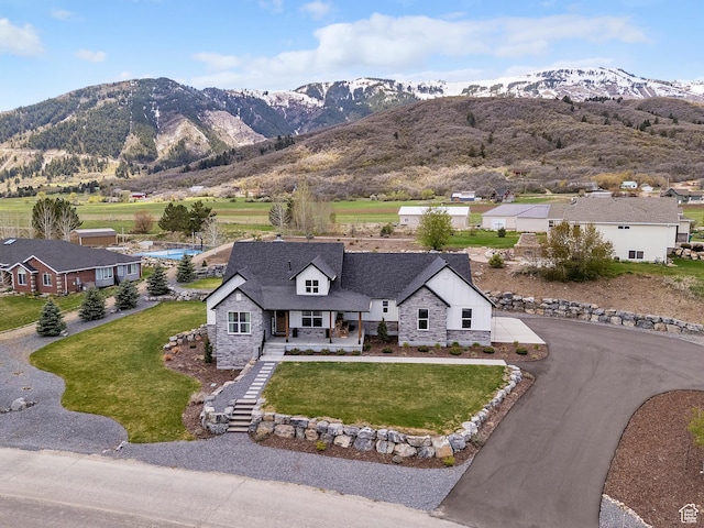view of front of home with stone siding, covered porch, a mountain view, and driveway