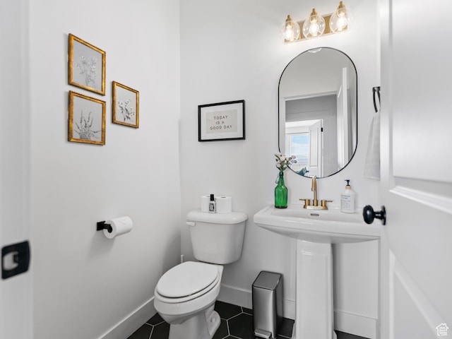 bathroom featuring toilet, tile patterned flooring, and baseboards