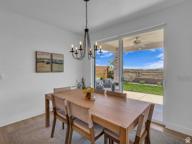 dining space featuring wood finished floors, a chandelier, baseboards, and ceiling fan