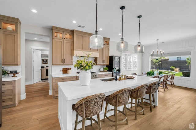 762 E Arina Way, Washington, UT 84780 - kitchen with a sink, light wood-style floors, a breakfast bar area, a kitchen island with sink, and light countertops