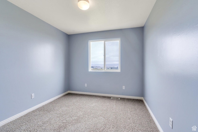spare room featuring carpet and baseboards