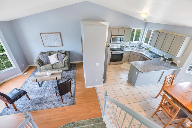 living room featuring vaulted ceiling, light wood finished floors, and baseboards