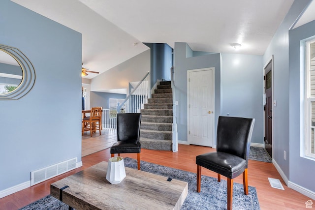 living room featuring stairway, lofted ceiling, ceiling fan, and wood finished floors