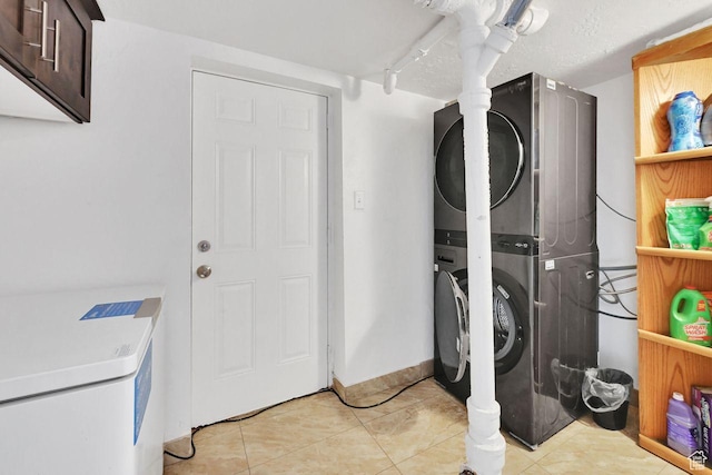 clothes washing area featuring stacked washer and clothes dryer and light tile patterned floors