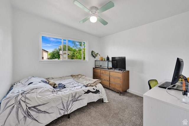 bedroom featuring light colored carpet, a desk, baseboards, and a ceiling fan