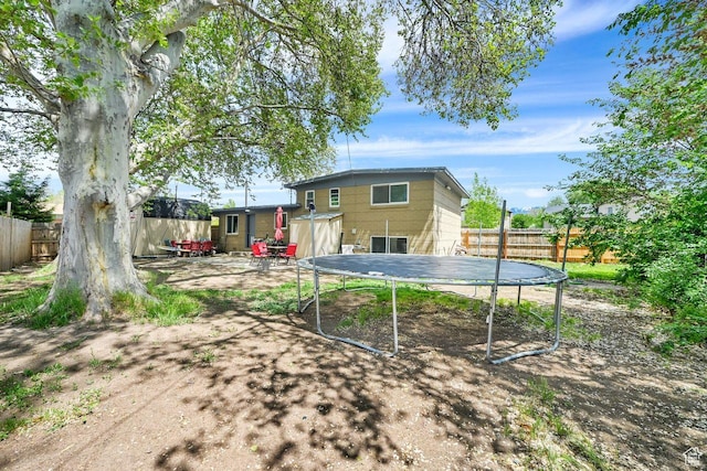 back of property featuring a trampoline and a fenced backyard