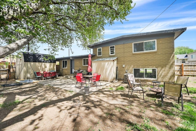 rear view of property with fence, a patio area, outdoor dining area, an outbuilding, and a shed