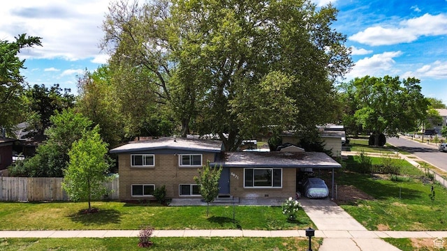 tri-level home with driveway, an attached carport, and brick siding