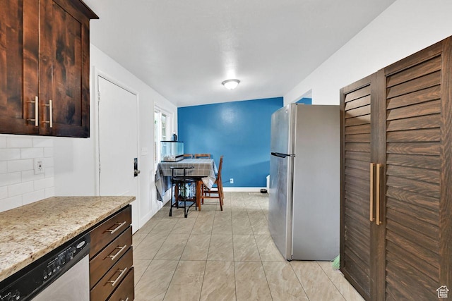 kitchen with appliances with stainless steel finishes, backsplash, dark brown cabinets, baseboards, and light stone countertops