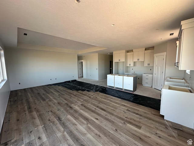 1127 N 3325 W Unit Yucca, Cedar City, UT 84721 - kitchen featuring open floor plan, hardwood / wood-style floors, a textured ceiling, white cabinets, and a kitchen island