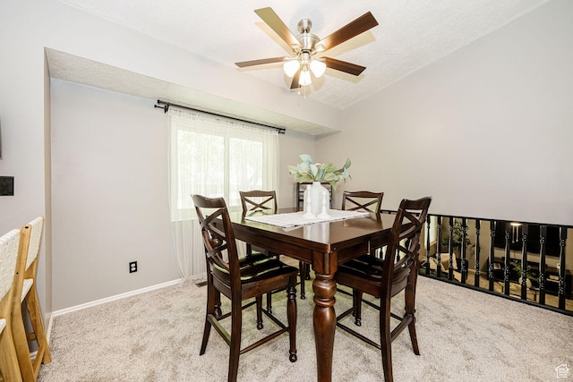 dining area with light colored carpet, a ceiling fan, a textured ceiling, and baseboards