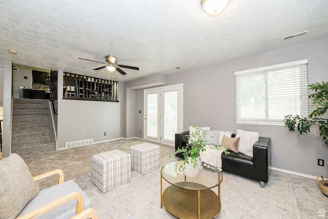 living room featuring a ceiling fan, healthy amount of natural light, carpet flooring, and a textured ceiling