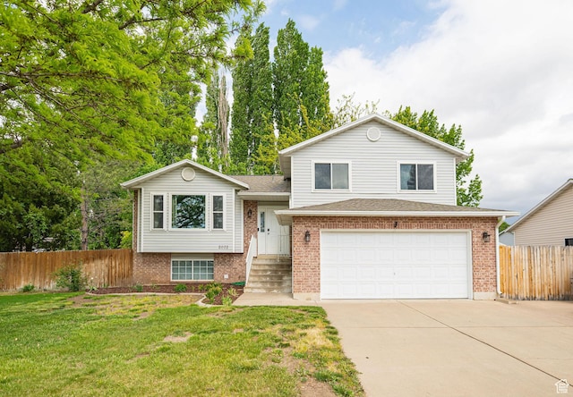 tri-level home featuring driveway, a garage, brick siding, and roof with shingles
