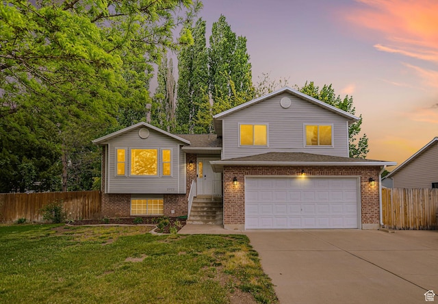 tri-level home featuring driveway, a garage, brick siding, and a shingled roof
