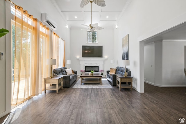 living room with a wall unit AC, ornamental molding, wood finished floors, a glass covered fireplace, and ceiling fan