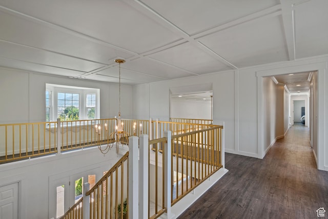 hall with an upstairs landing, wood finished floors, coffered ceiling, baseboards, and a decorative wall