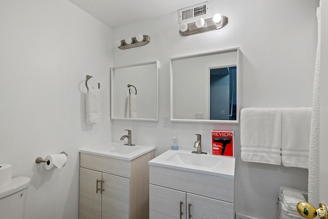 bathroom featuring two vanities and toilet