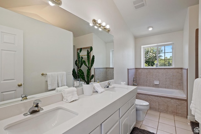 bathroom featuring tile patterned flooring, tiled tub, lofted ceiling, toilet, and double vanity