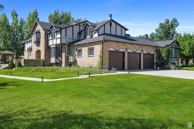tudor house featuring an attached garage, a front lawn, driveway, and brick siding