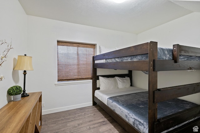 bedroom featuring wood finished floors, baseboards, and lofted ceiling