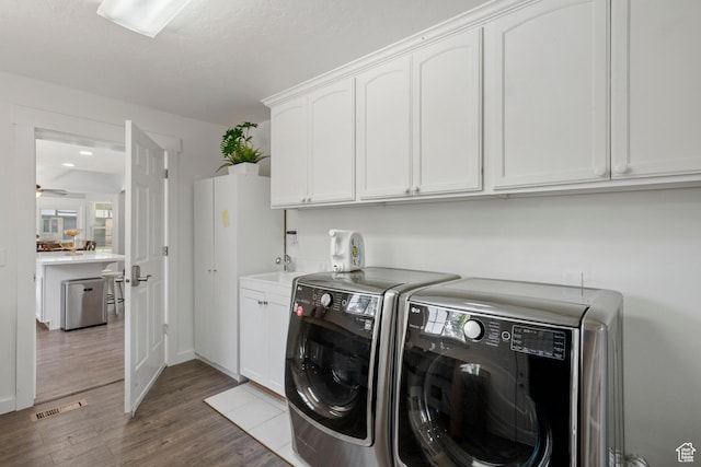 laundry area featuring separate washer and dryer, cabinet space, dark wood finished floors, and plenty of natural light