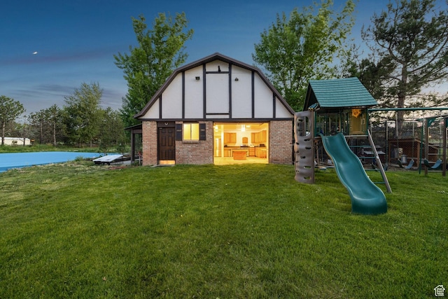1890 W Rock Hollow Rd, Bluffdale, UT 84065 - back of property at dusk featuring a playground, a lawn, brick siding, and an outbuilding