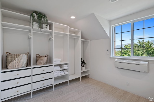 spacious closet with an AC wall unit and wood finished floors