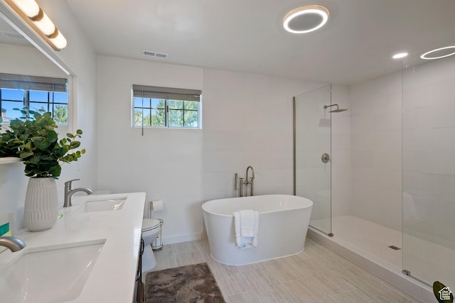 full bathroom featuring tiled shower, a soaking tub, double vanity, and toilet