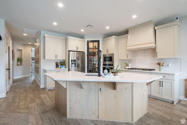 2883 S 3640 W, Hurricane, UT 84737 - kitchen featuring appliances with stainless steel finishes, custom exhaust hood, a center island with sink, decorative backsplash, and light countertops
