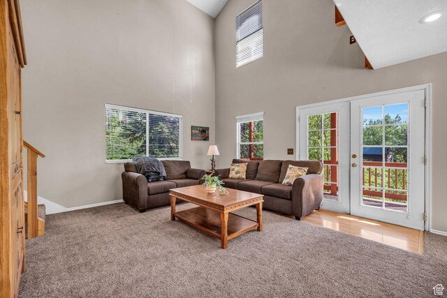 living area featuring carpet flooring, a high ceiling, baseboards, french doors, and stairs