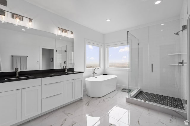 bathroom with recessed lighting, a stall shower, double vanity, a freestanding bath, and marble finish floors